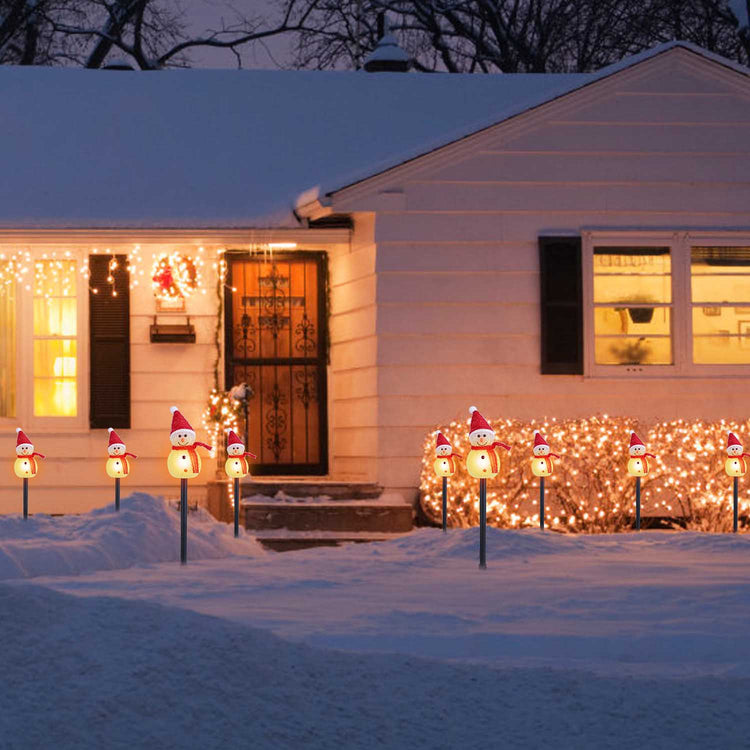 a house with snow covered yard with snowman decorations