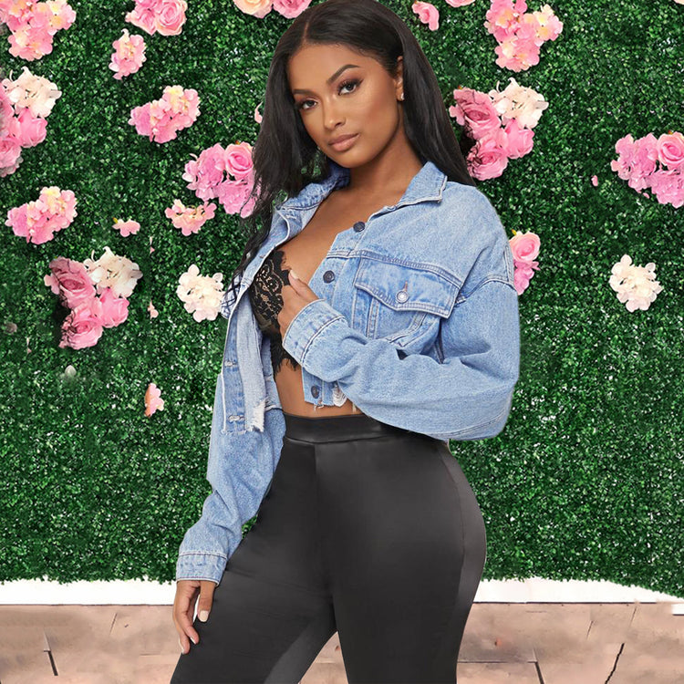 a woman posing in front of a wall of flowers