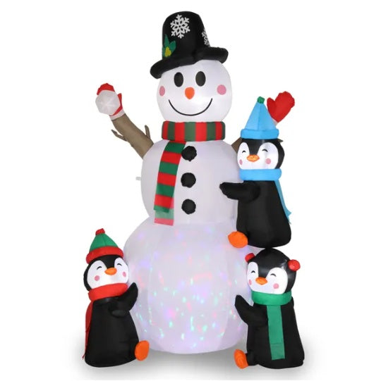 a group of penguins standing next to a snowman